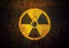 Yellow radiation warning symbol on rusty metal surface.