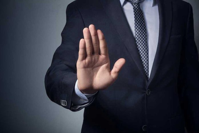 611111144 Man in suit with hand raised, signaling stop.