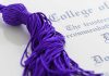 Close-up of a purple graduation tassel next to a diploma