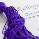 Close-up of a purple graduation tassel next to a diploma