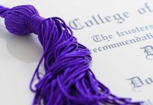 Close-up of a purple graduation tassel next to a diploma