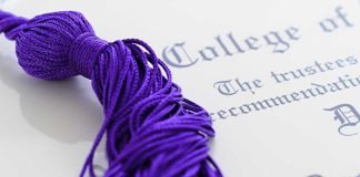 Close-up of a purple graduation tassel next to a diploma