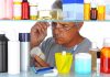Senior man looking closely at a product in a medicine cabinet filled with various bottles and containers