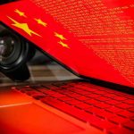 Judge STRIPS Citizenship From Chinese Spies Laptop screen displaying Chinese flag and code.